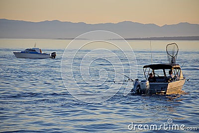 Sportfishing boats troll for salmon near Ogden Point on a sunny summer evening in August Editorial Stock Photo