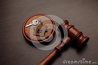 Judge gavel and key chain in shape of two splitted part of house on wooden background. Concept of real estate auction or Stock Photo