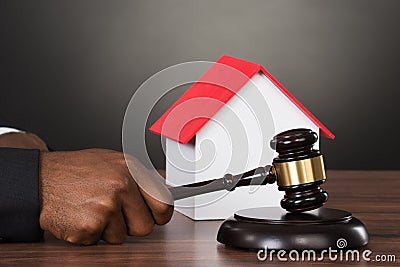 Judge Hands Hitting Gavel With House Model Stock Photo