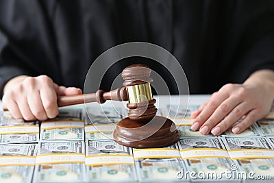 Judge holds wooden gavel on dollar banknotes close-up. Stock Photo