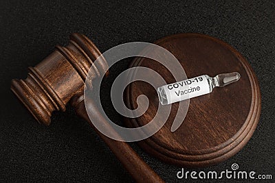 Judges gavel and glass ampoule vial with coronavirus COVID-19 vaccine. Concept laws against covid-19 Stock Photo