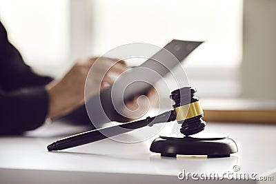 Judicial mallet on table and paper document in judge hand on blurred background Stock Photo