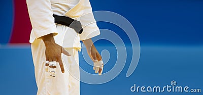 Judo fighter poses in white kimono with black belt. Japanese judo and jiu jitsu. Professional sport concept. Horizontal sport post Stock Photo