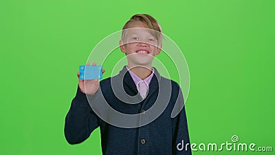 Jugendlicher schaut herum und zeigt dann eine Kreditkarte auf einem grünen Schirm stock video Jugendlicher schaut herum und zeigt dann eine Kreditkarte auf einem grünen Schirm stock video