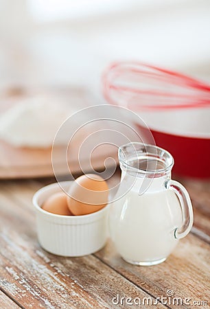 Jugful of milk, eggs in a bowl and flour Stock Photo