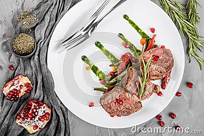 Juicy medium beef fillet steaks mignon with green beans, pomegranate and sauce in plate on grey background. Hot Meat Dishes, top Stock Photo