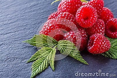 Juicy fresh natural raspberries on a dark stone background Stock Photo