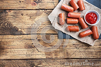 Juicy grilled half meat sausages with tomato sauce and ketchup on a wooden background. Fat fast food. Concept unhealthy Stock Photo