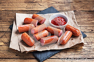 Juicy grilled half meat sausages with tomato sauce and ketchup on a wooden background. Fat fast food. Concept unhealthy Stock Photo