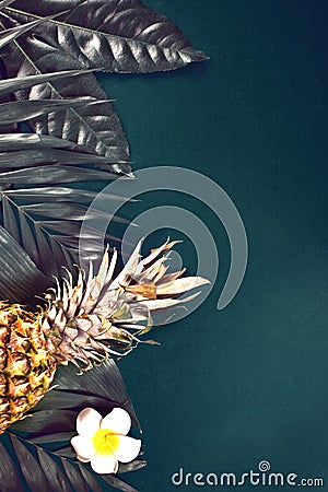 Juicy pineapple, palm leaf and flower Plumeria frangipani on dark green background. Copy space. Top view Stock Photo