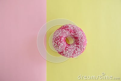 Juicy Pink Sprinkled Donut isolated on a Pink and Yellow Background Stock Photo