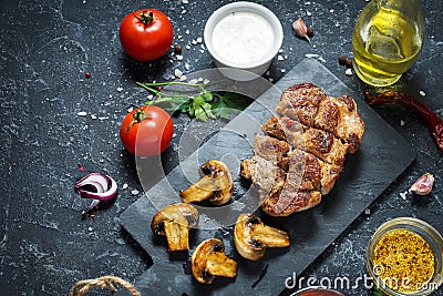 Juicy pork steak with spices and grilled mushroomson dark stone background Stock Photo