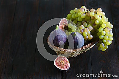 Juicy raisins and several ripe figs in a fruit basket on a white and dark wooden background. fresh fruits, natural vitamin Stock Photo
