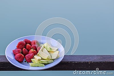 Juicy red strawberries are paired with crunchy, sweet green raw mangoes on a plate for customers to choose after last meal, and Stock Photo