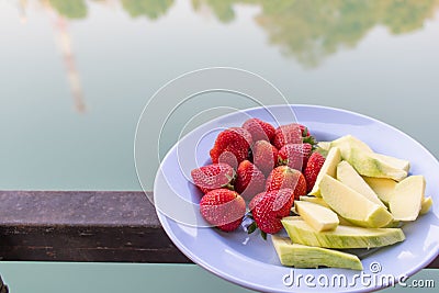 Juicy red strawberries are paired with crunchy, sweet green raw mangoes on a plate for customers to choose after last meal, and Stock Photo