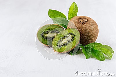 Juicy ripe green kiwi with wet slice section, young leaf on white wood background, closeup, border. Stock Photo