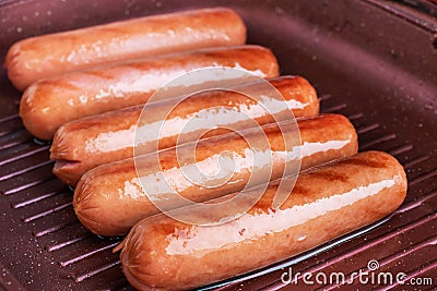 Juicy sausages roasted on the grill pan. Close up. Stock Photo