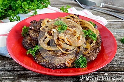 Juicy slices of fried liver and onions on a red plate Stock Photo