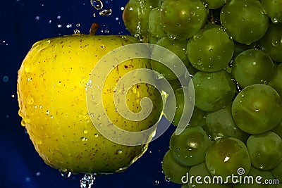 Juicy yellow apple and Green grape with water drops on a blue background Stock Photo