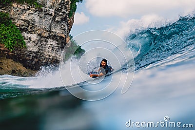 July 12, 2020. Bali, Indonesia. Surfer ride on bodyboard at wave. Surfing in Padang Padang Editorial Stock Photo