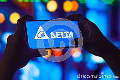 July 11, 2022, Brazil. In this photo illustration, a silhouetted woman holds a smartphone with the Delta Electronics, Inc. logo Cartoon Illustration