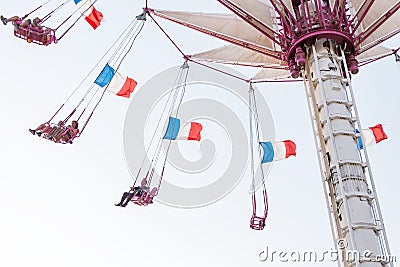 People relax in an amusement Park on a high-rise carousel with French flags waving in the wind Editorial Stock Photo