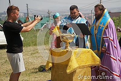 July 11, 2020, Russia, Magnitogorsk. Photographer-reporter takes pictures of Orthodox priests performing outdoor services Editorial Stock Photo