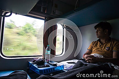 July 4th 2022 Haridwar India. A man inside a moving train looking outside of the window and enjoying the view. Ac Two tier coach Editorial Stock Photo