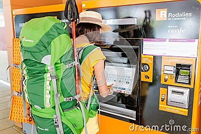 Traveler woman buying a ticket at a publice transport ticket vending machine Renfe at the train station Editorial Stock Photo