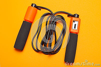 Jump rope. Fun exercises for body health. Orange rope with jump counter with black cord. Yellow orange background Stock Photo