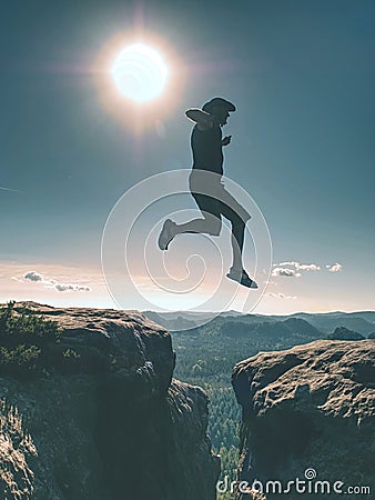 Jumping against Sun. Jumps over cliff. Man on trail through rocks/J Stock Photo