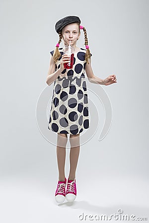 Jumping Caucasian Girl With Pigtails Posing in Gray Velvet Cap and Polka Dot Dress Stock Photo