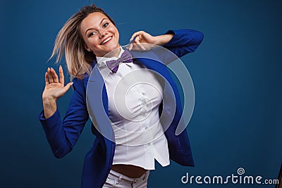 Jumping and dancing businesswoman in stylish blue jacket and bow tie. Portrait of a cheerful girl Stock Photo