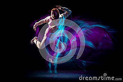 One energy young flexible sportive man dancing hip-hop or breakdance in white outfit on dark background in mixed blue Stock Photo