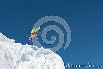 A jumping skier jumping from a glacier against a blue sky high in the mountains. Professional skiing Stock Photo