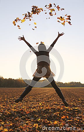 Jumping teenage girl, throwing leaves up in the air Stock Photo