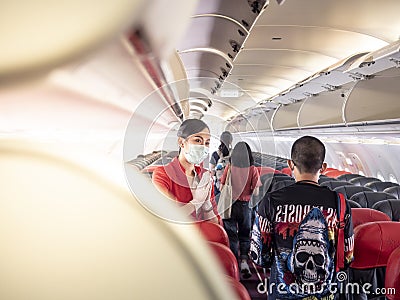 28 jun 20, Donmueng Airport, Bangkok, Thailand. Female cabin crew in red uniform greeting passenger in aircraft cabin during board Editorial Stock Photo