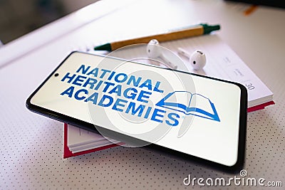 June 30, 2022, Brazil. In this photo illustration the National Heritage Academies logo seen displayed on a smartphone next to a Cartoon Illustration