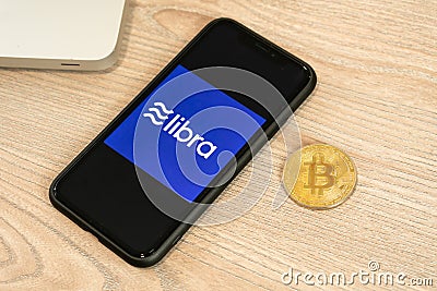 18 June 2019, Ljubljana Slovenia - smartphone with Libra logo on it, next to Bitcoin coin. Facebook`s new global Editorial Stock Photo
