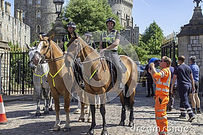 Mounted Police Officers on crowd control duty on the streets outside Royal Windsor Castle an official Royal Residence in Berkshire Editorial Stock Photo