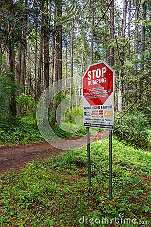 June 2022 - Nanaimo, Canada: No Dumping sign and hiking trail in green forest. Editorial Stock Photo