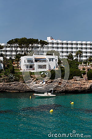 June 16th, 2017, Cala Ferrera, Mallorca, Spain - boat parked in front of a house with stairs leading up the rocks Editorial Stock Photo