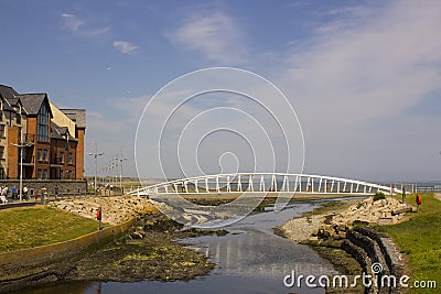 Visitors crossing the modern footbridge at the mouth of the Shimna River on the seafront in Newcastle County Down Northern Ireland Editorial Stock Photo