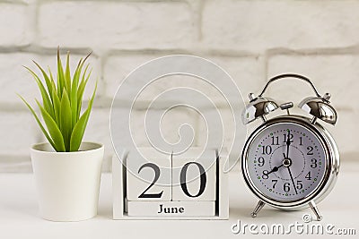 June 20 on a wooden calendar next to the alarm clock on the table. Summer day, empty space for text.Calendar for June on a light Stock Photo