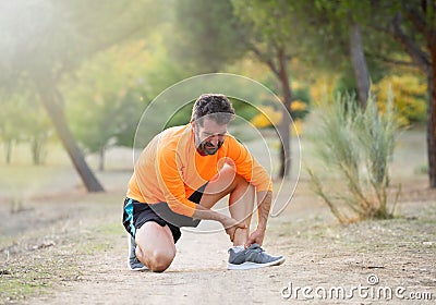 Jung runner man touching foot in pain due to sprained broken or twisted ankle while running Stock Photo