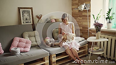 Junge Frau, die auf Couch und strickender woolen Strickjacke sitzt stock video Junge Frau, die auf Couch und strickender woolen Strickjacke sitzt stock video