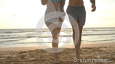 Junges glückliches Paar, das auf den Strand und das Händchenhalten von einander bei Sonnenuntergang geht Mann und Frau, die auf S Junges glückliches Paar, das auf den Strand und das Händchenhalten von einander bei Sonnenuntergang geht Mann und Frau, die auf S
