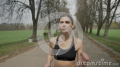 Junges Sportmädchen läuft mit Kopfhörern im Park im Sommer, gesunder Lebensstil, Sportkonzeption Junges Sportmädchen läuft mit Kopfhörern im Park im Sommer, gesunder Lebensstil, Sportkonzeption