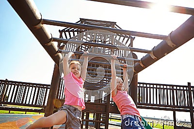 Jungle gym adventures. two little girls hanging on the monkey bars at the playground. Stock Photo