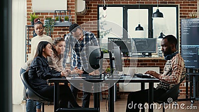 Junior developers collaborating on group project compiling algorithm asking senior programer for help Stock Photo